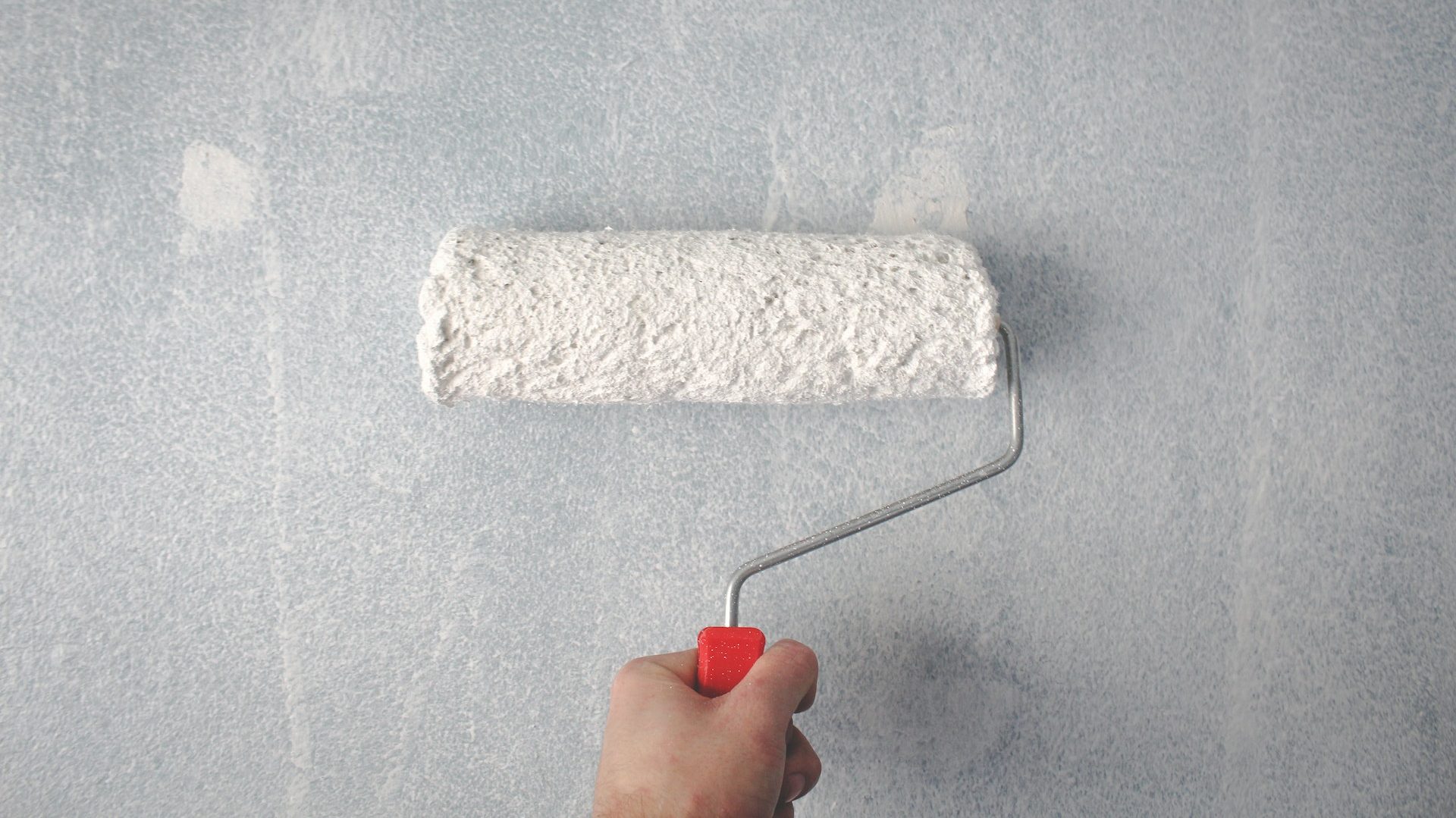 Person Holding Paint Roller On Wall