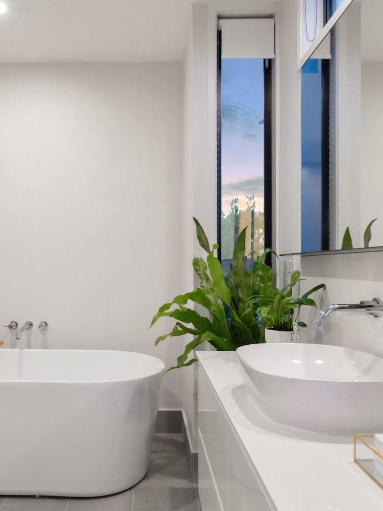 white ceramic bathtub near green potted plant